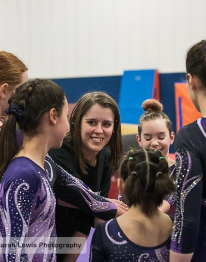 Gymnasts huddle around their coach for a pep talk. 