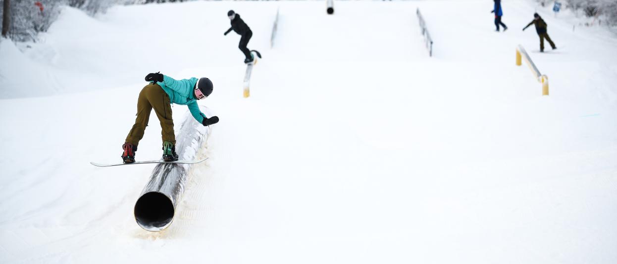 Snowboarders navigate the Mount Sima terrain park